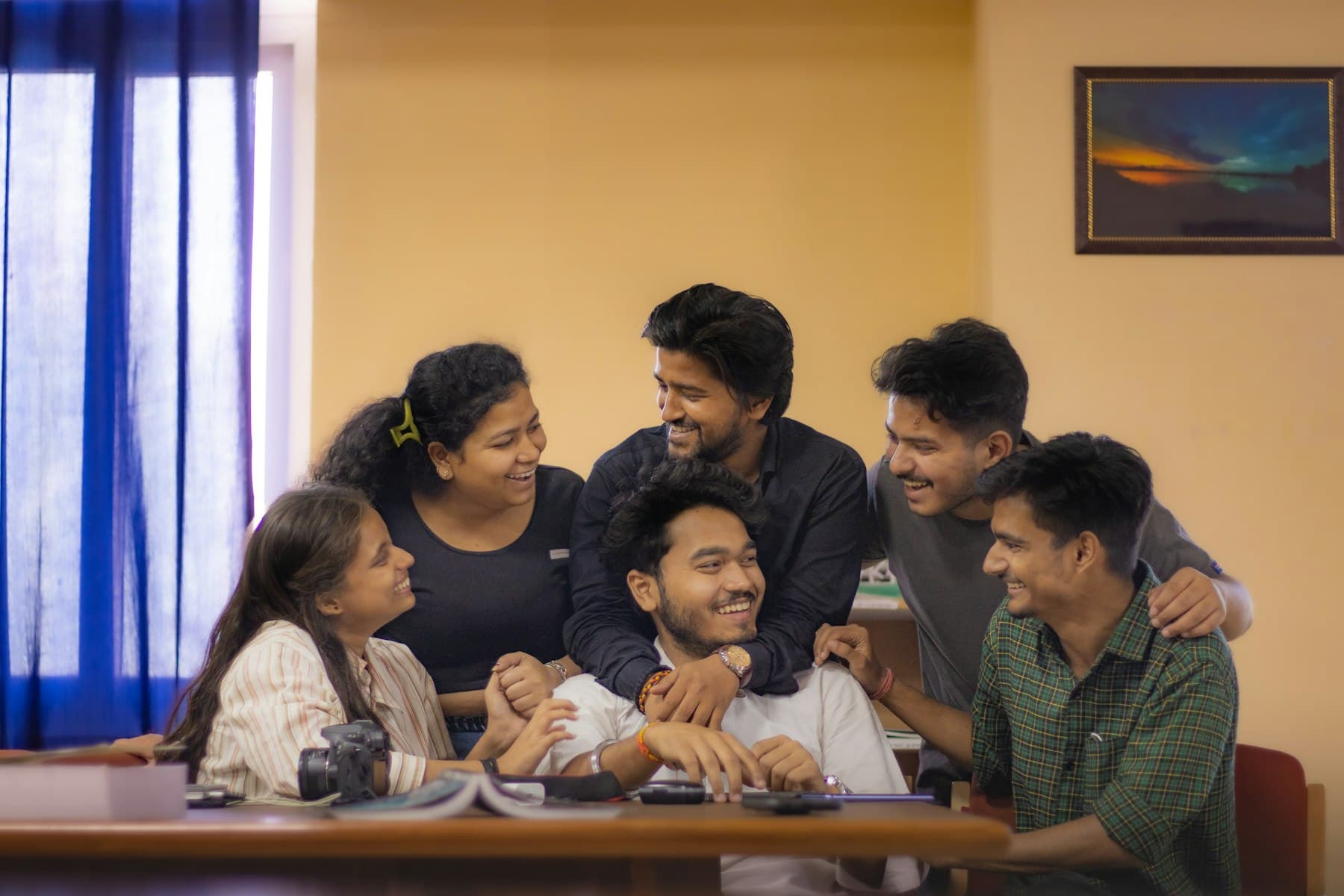 A group of students laughing together around a study table at home
